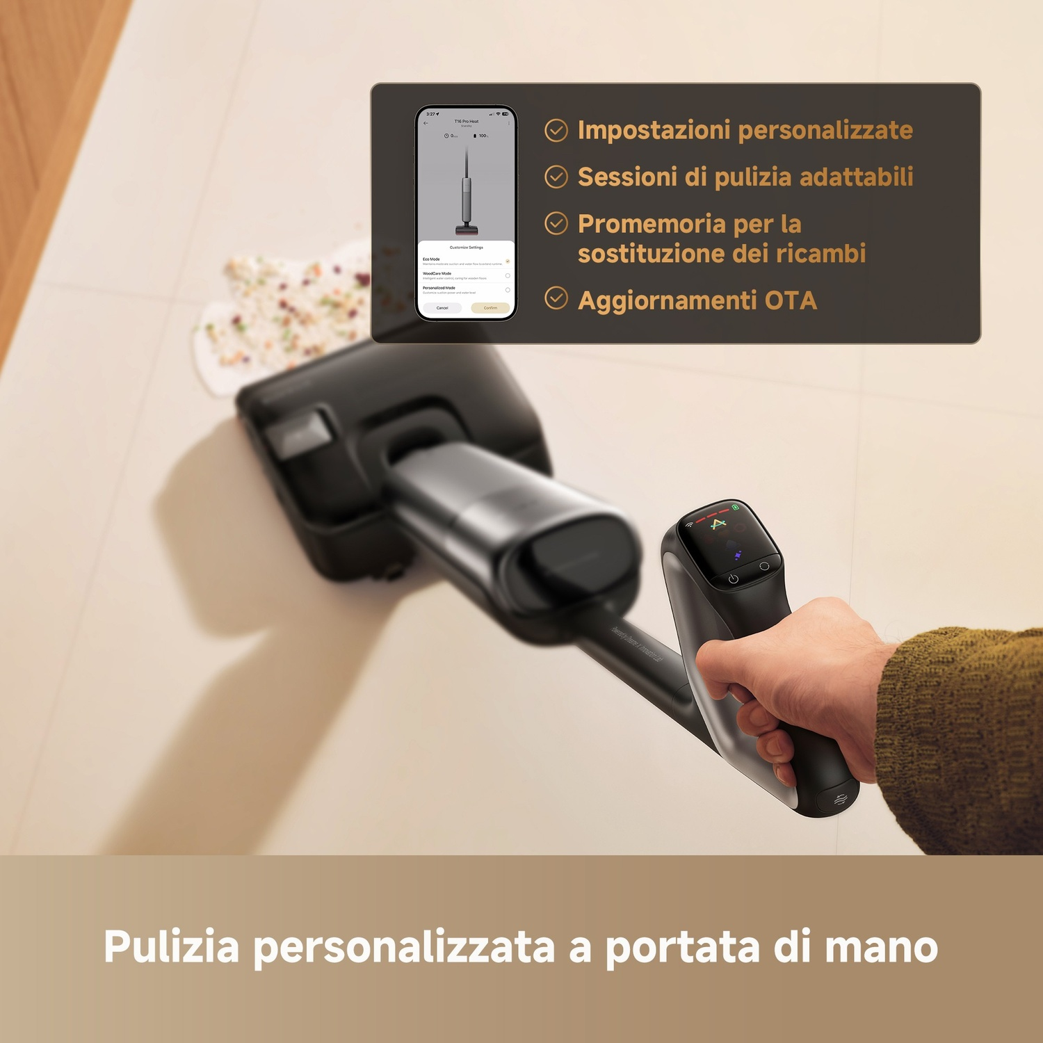 Una mano tiene un manico di aspirapolvere con schermo; un telefono con impostazioni è vicino.