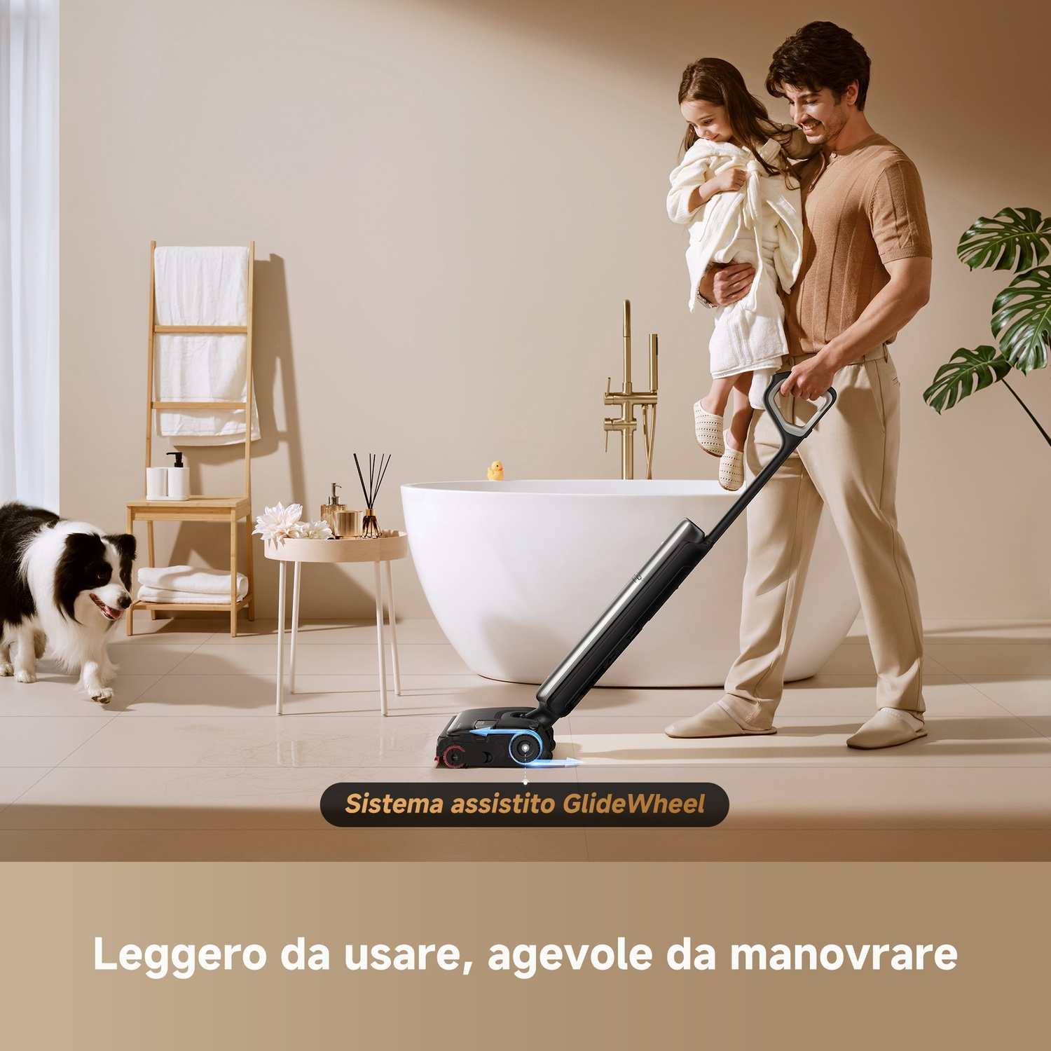 Uomo regge bimba, pulisce pavimento con aspiratore. Cane osserva. Bagno.