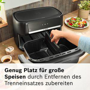 Schwarze Heißluftfritteuse mit entnommenem Einsatz, daneben eine Schüssel mit Dip.