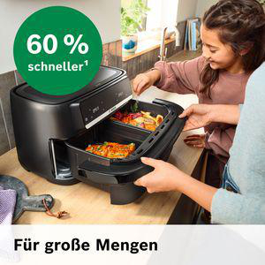 Ein Mädchen nimmt Essen aus einer schwarzen Heißluftfritteuse.
