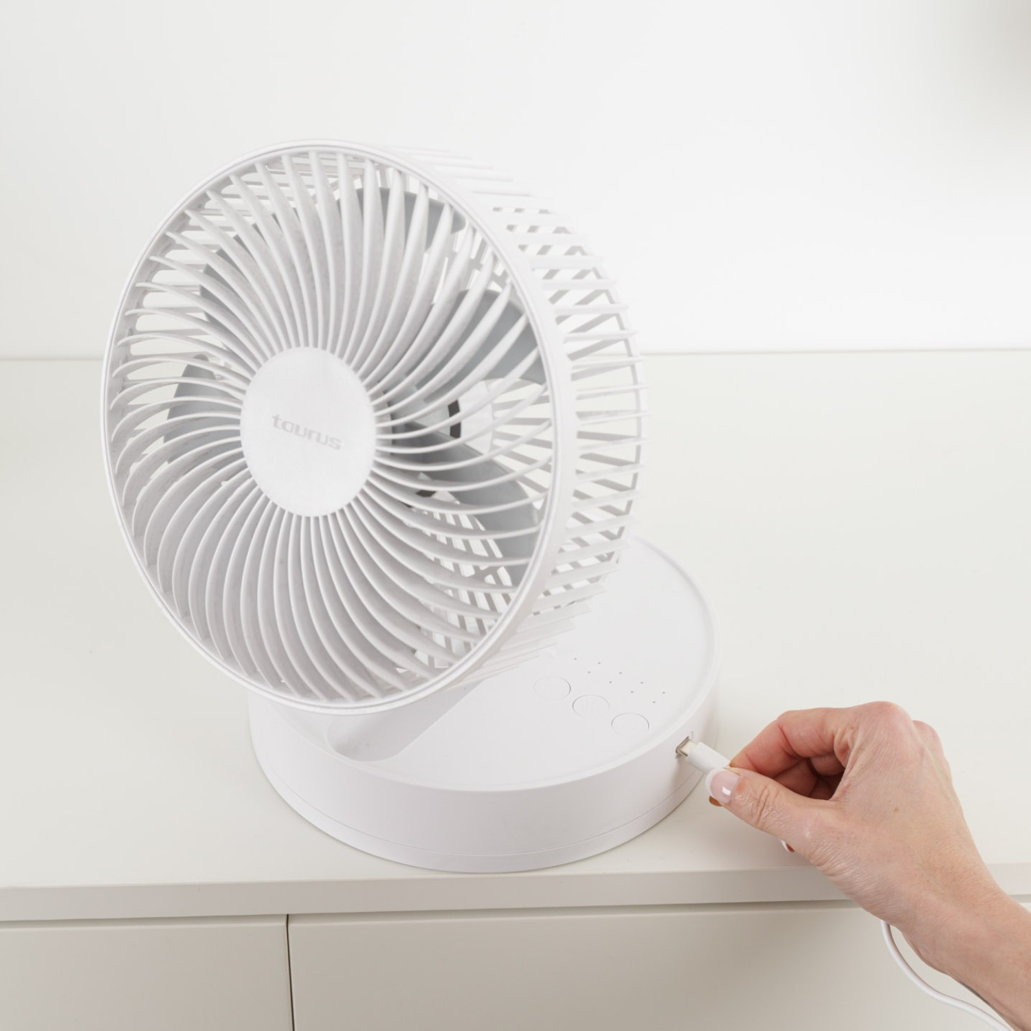 Un ventilador de escritorio blanco se está enchufando a una fuente de alimentación.