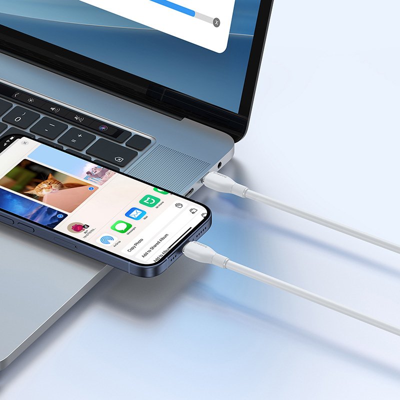 Egy okostelefon és laptop fehér kábelekkel csatlakoztatva.