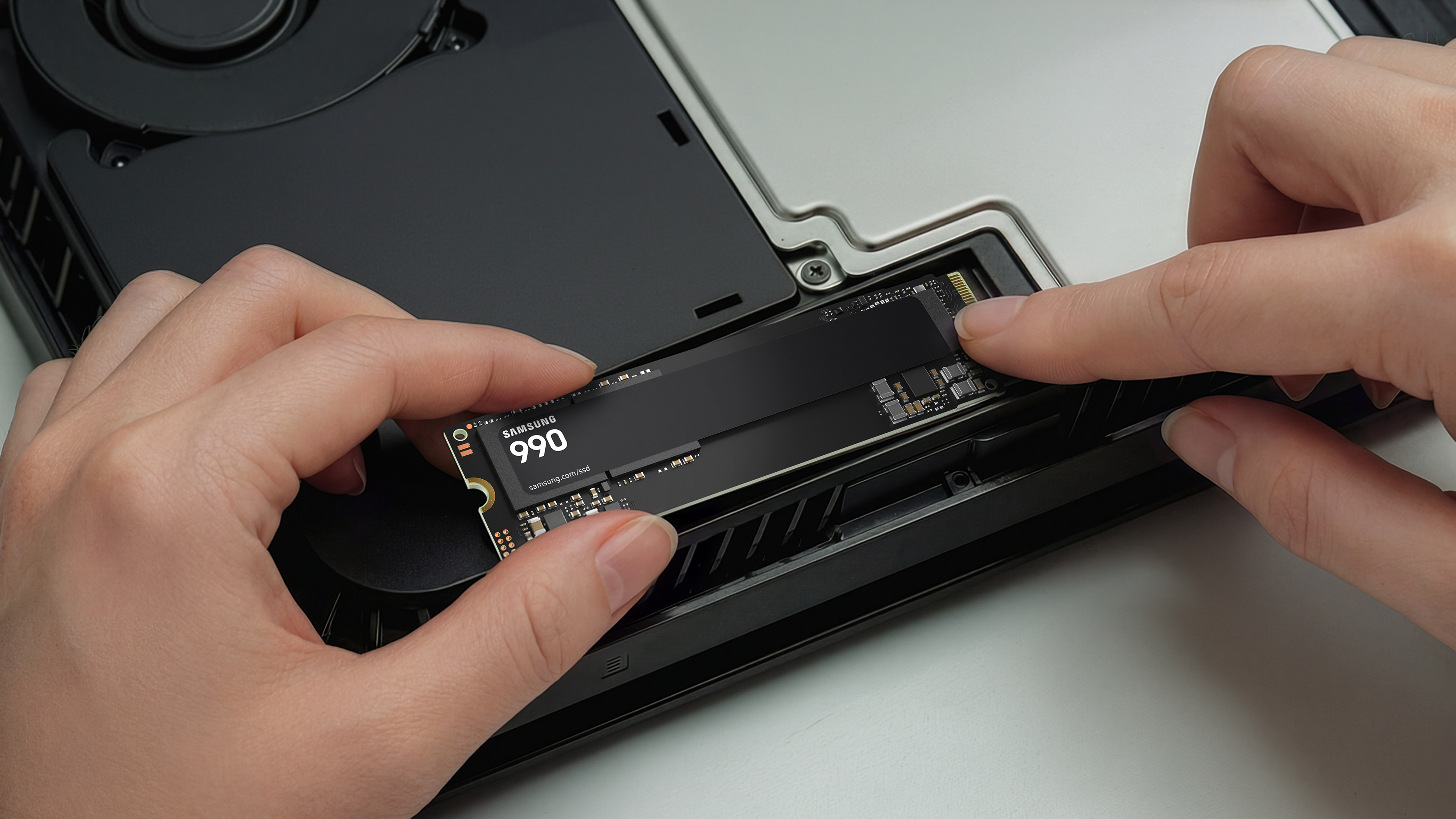 Hände setzen eine Samsung 990 SSD in einen Computer ein.