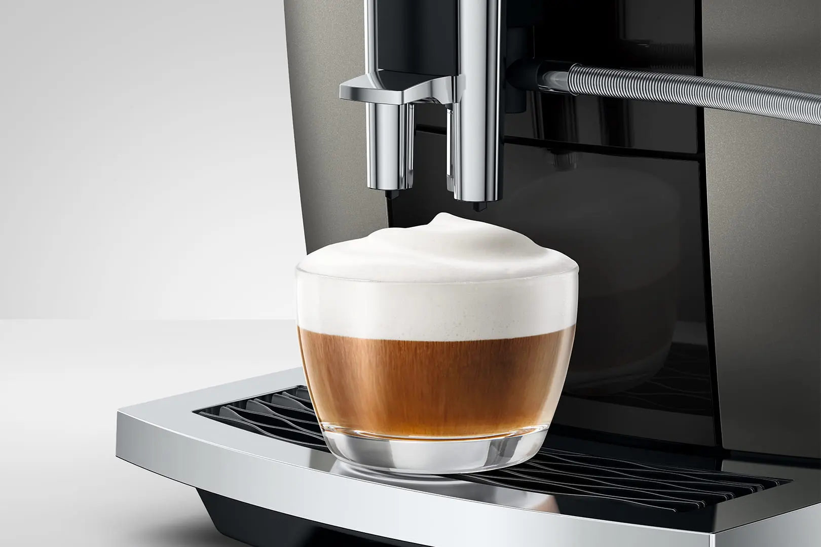 Macchina da caffè che prepara una bevanda con abbondante schiuma di latte in un bicchiere.