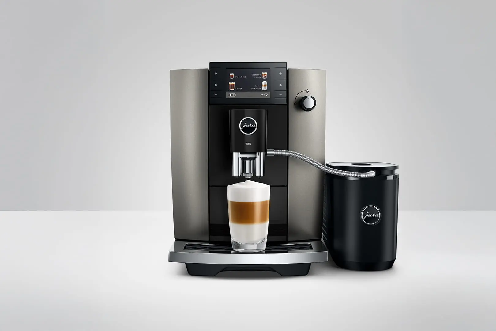 Una macchina da caffè argento e nera con un bicchiere di latte macchiato.