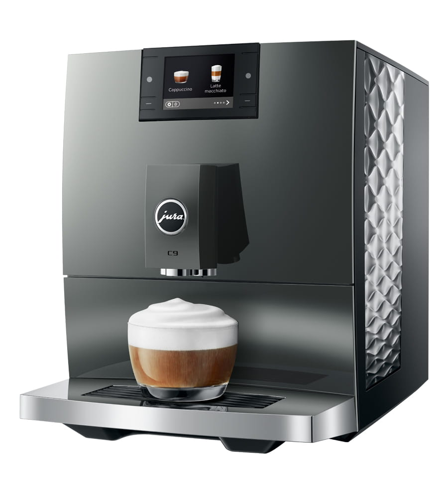Macchina da caffè grigia con bicchiere di schiuma cremosa in primo piano.
