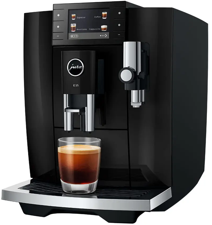 Una macchina da caffè Jura nera prepara un espresso in un bicchiere trasparente su un vassoio.