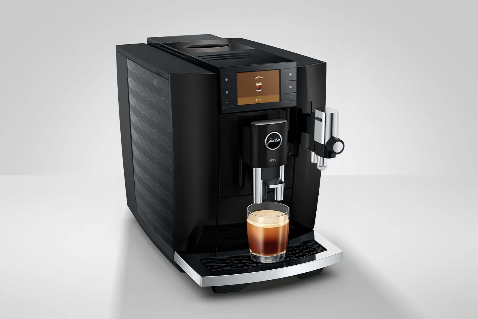 Macchina da caffè nera con un bicchiere di espresso e un display digitale.