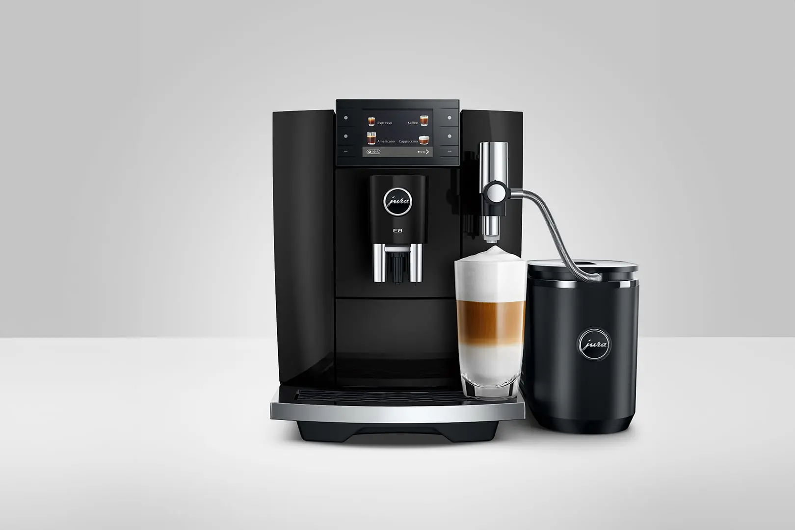 Macchina da caffè nera con caraffa per latte e un bicchiere di latte macchiato.