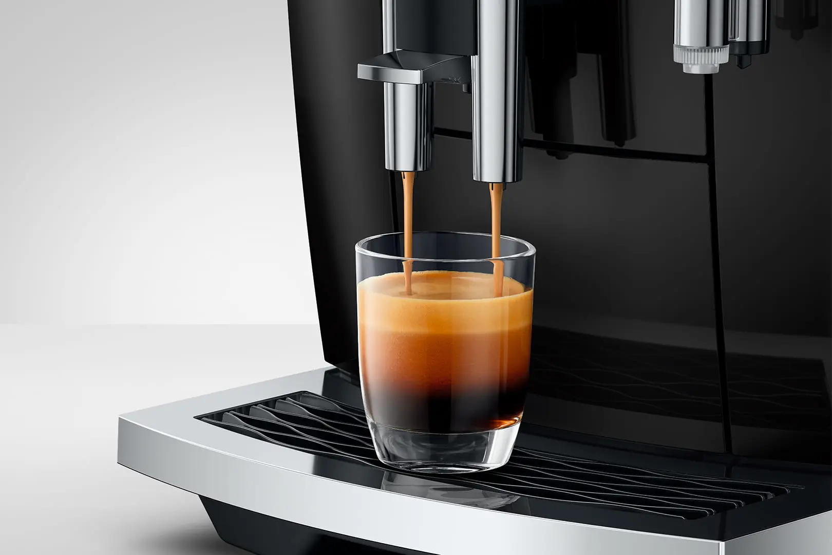 Macchina da caffè prepara un espresso in un bicchiere con crema.
