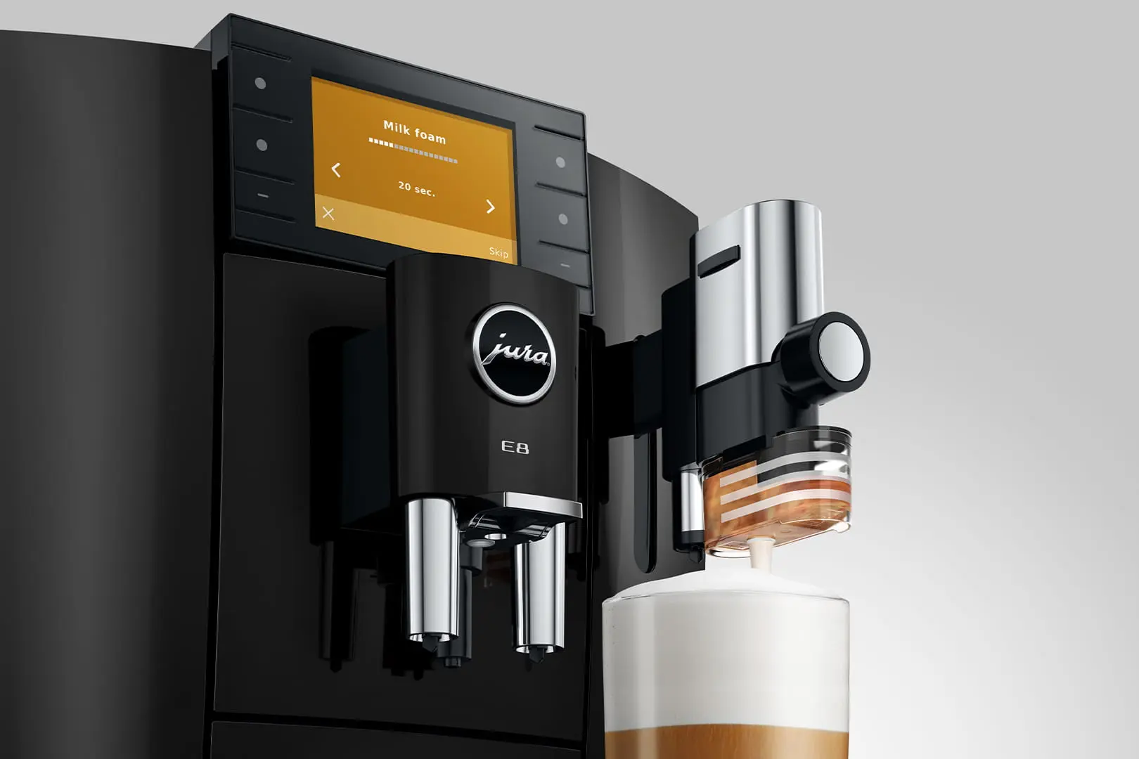 Una macchina da caffè Jura nera sta montando il latte in un bicchiere.