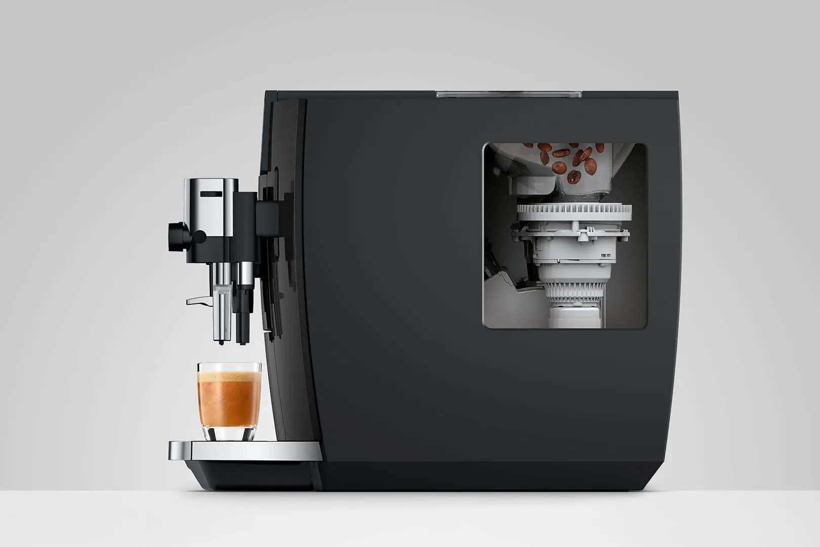 Macchina da caffè nera con bicchiere ed espresso, chicchi visibili all'interno.