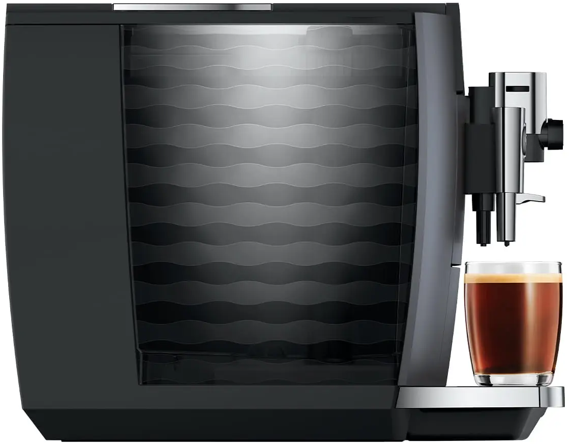 Macchina da caffè nera con un bicchiere di caffè accanto.
