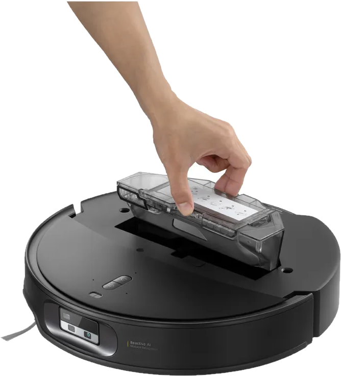 Une main insère un bac à poussière transparent dans un robot aspirateur noir.