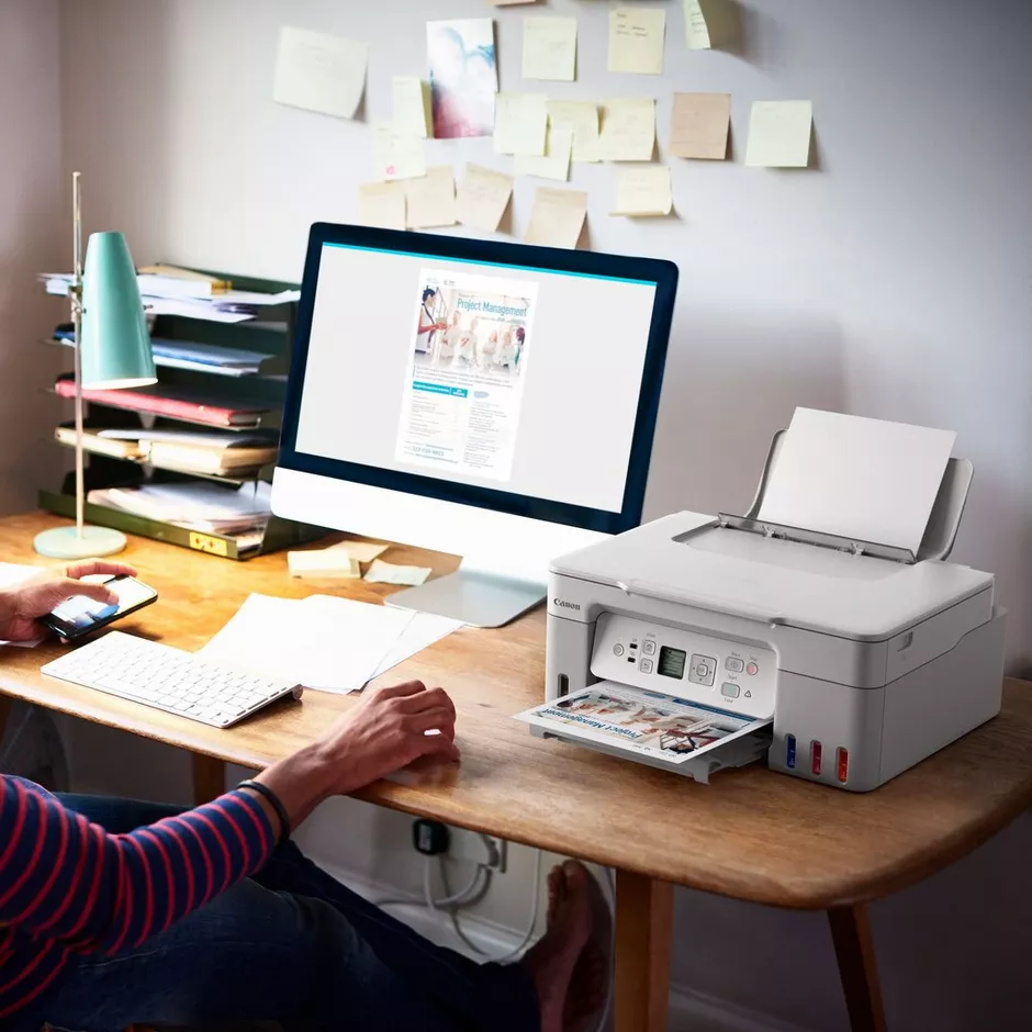 Ein Mann sitzt an einem Schreibtisch mit einem Computer und Drucker.