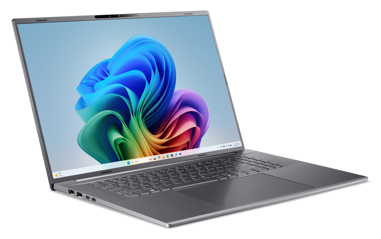 Szary laptop z jasnym ekranem wyświetlającym kolorowy wzór abstrakcyjny.