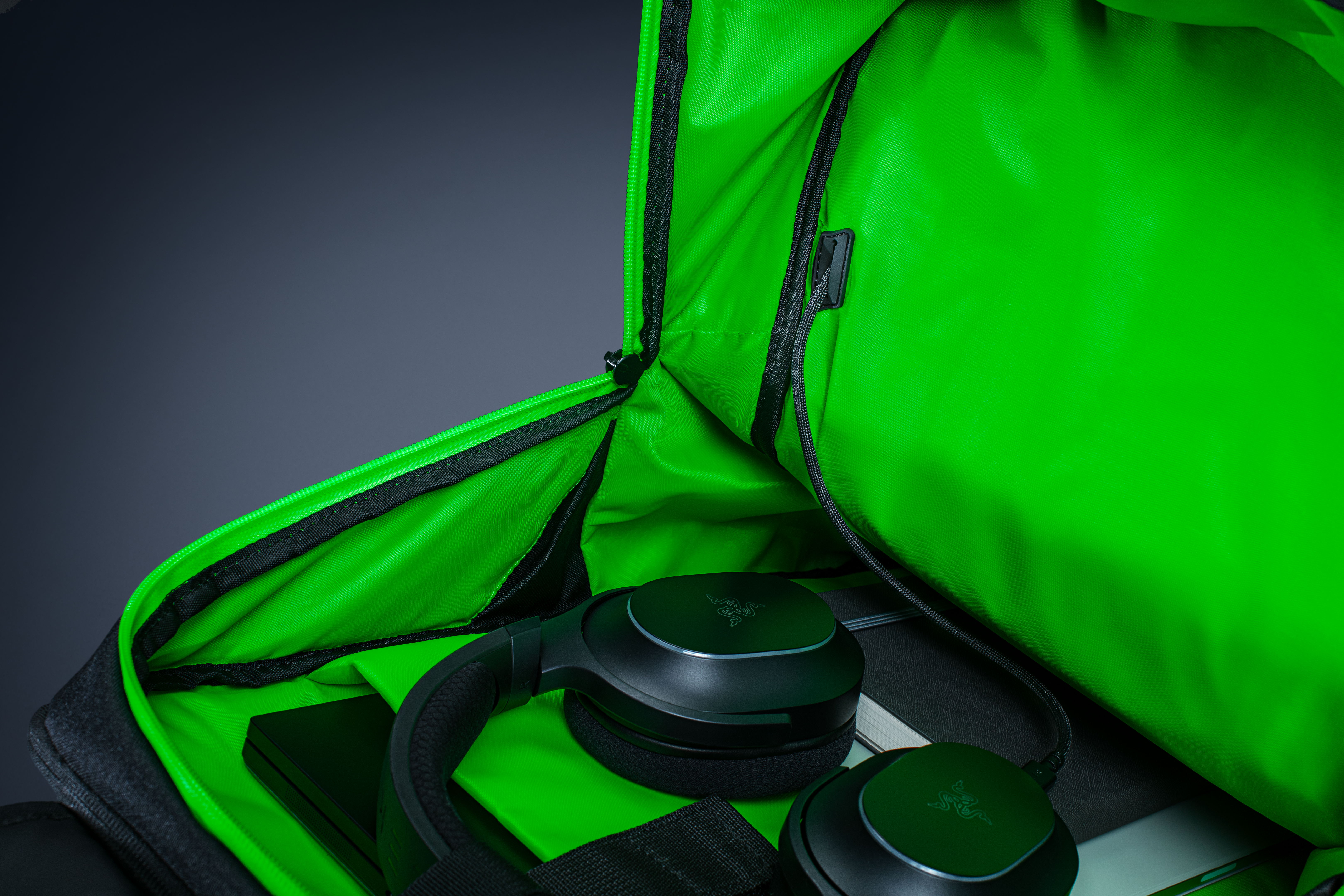 Ein offener Rucksack mit leuchtend grünem Innenfutter und schwarzen Kopfhörern.
