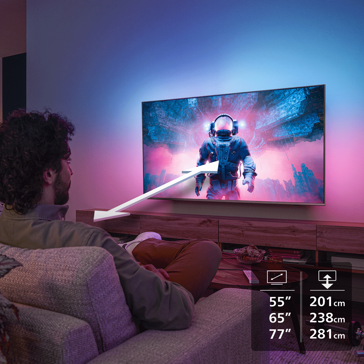 Mann auf Couch sieht Astronauten-Spiel auf dem Fernseher. Größen: 55", 65", 77".