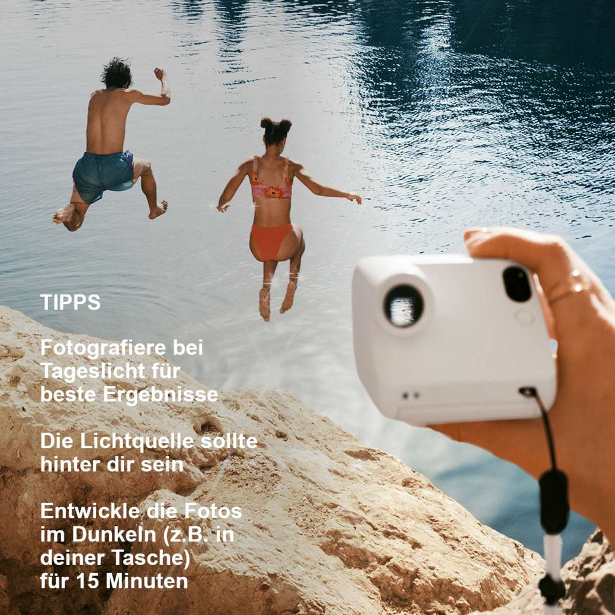 Zwei Personen springen ins Wasser, eine Hand hält eine weiße Kamera.