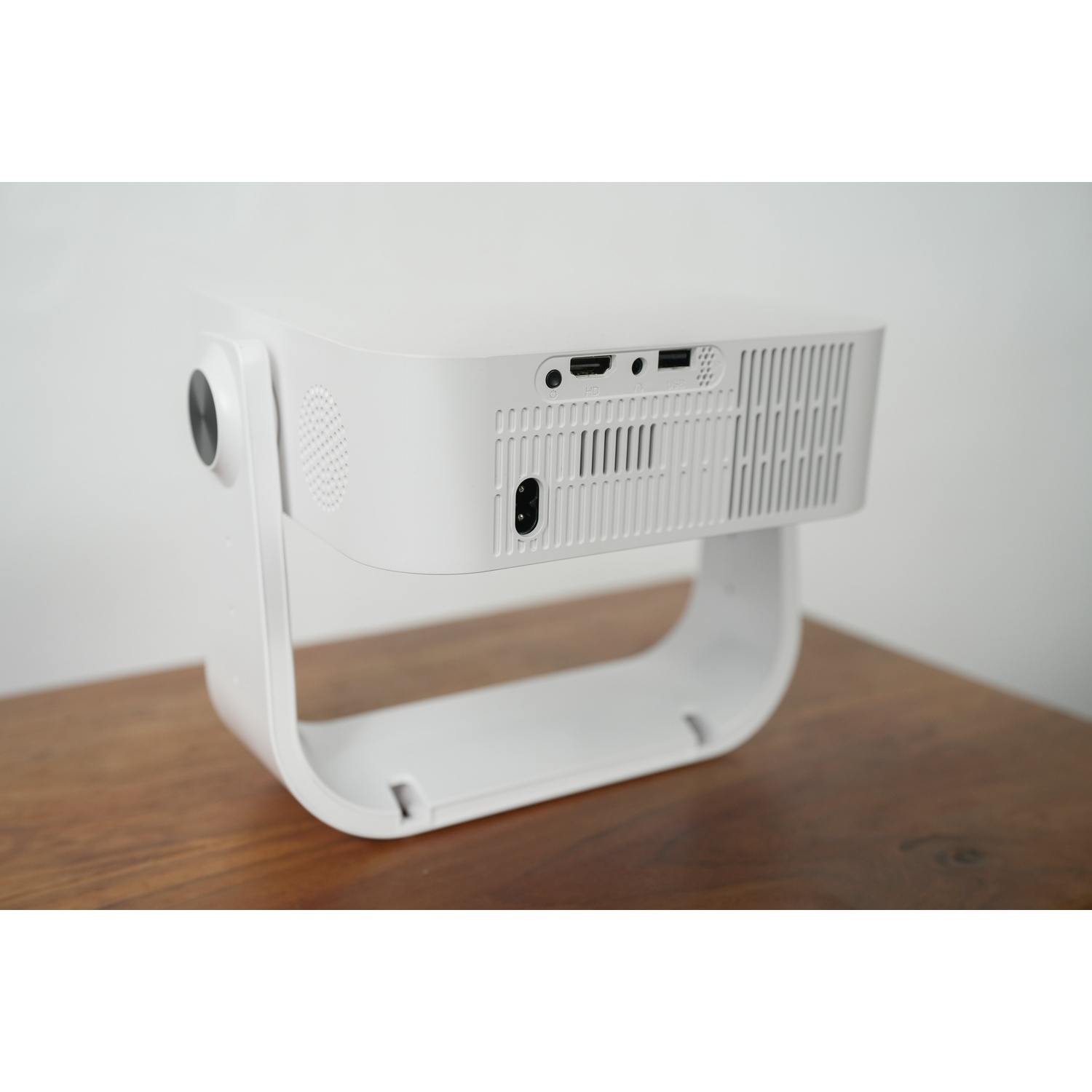 Un proiettore bianco con porte HDMI e USB su un tavolo di legno.
