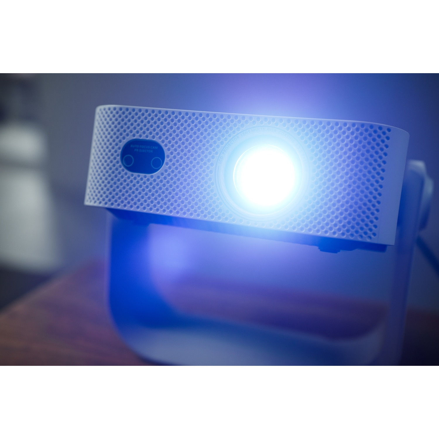 Un proiettore bianco emette una brillante luce blu, appoggiato su un supporto blu.