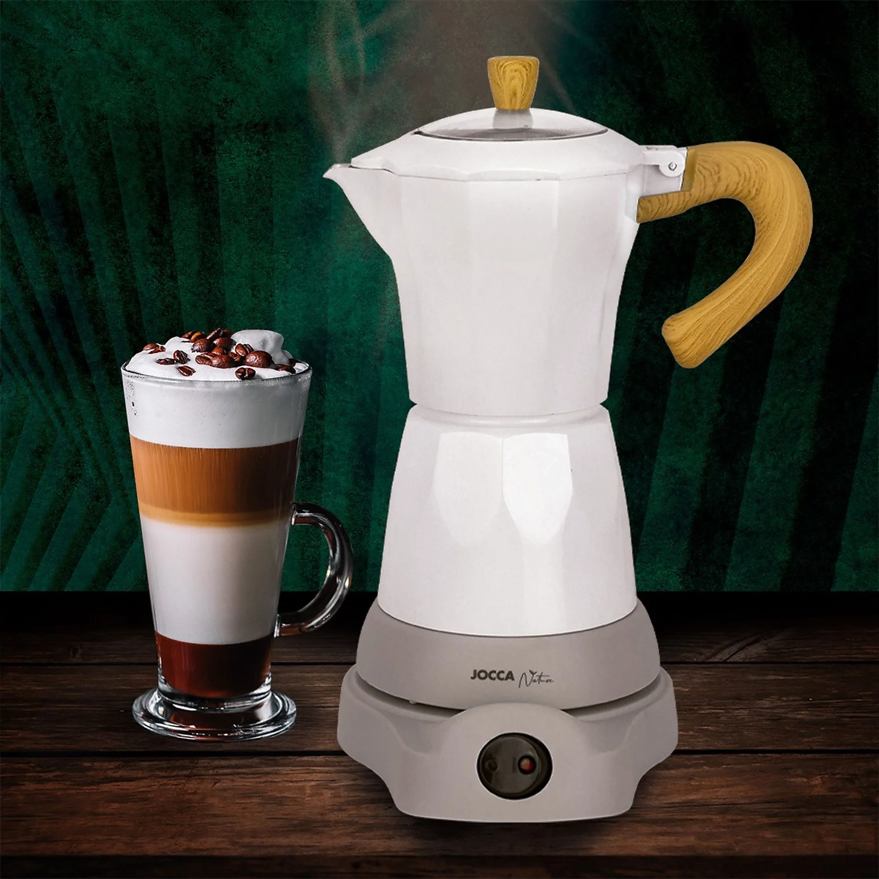 Una cafetera blanca con mangos de madera junto a un latte macchiato con granos de café.