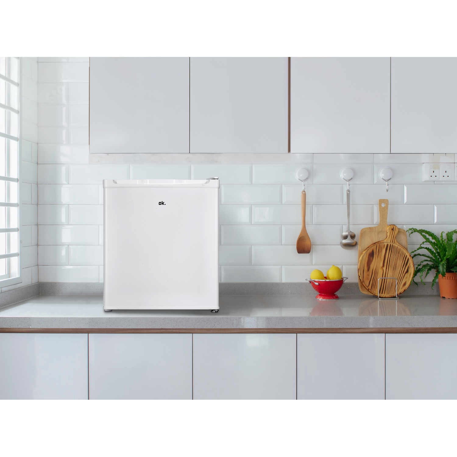 Un mini-frigo bianco su un bancone da cucina con utensili.