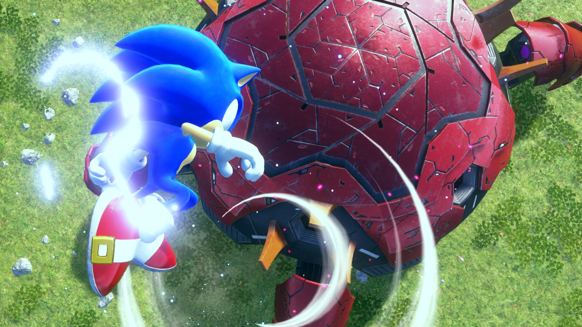 Sonic rennt auf eine große rote Maschine zu, umgeben von grüner Wiese und Felsen.