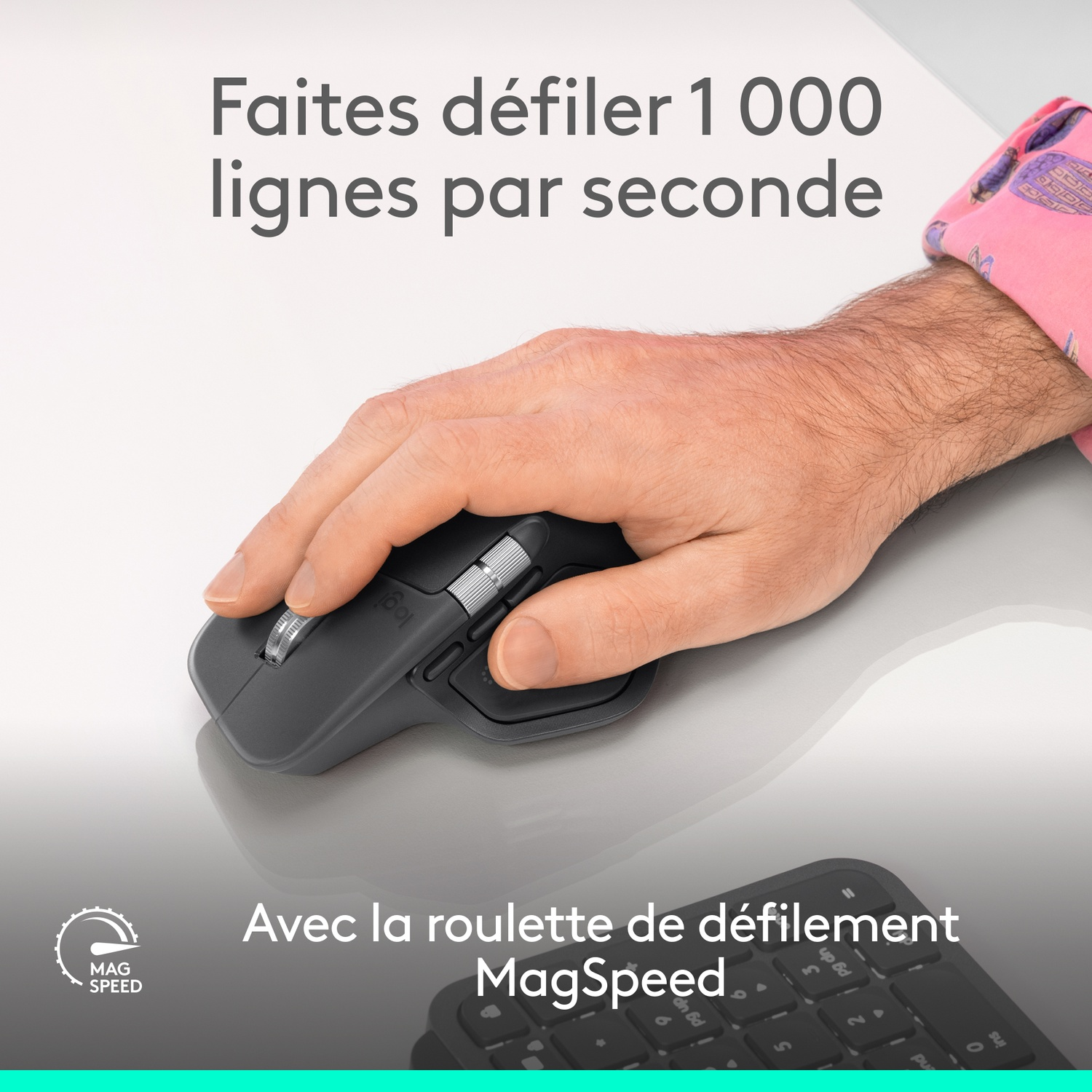 Une main utilise une souris Logitech avec molette MagSpeed sur un clavier.