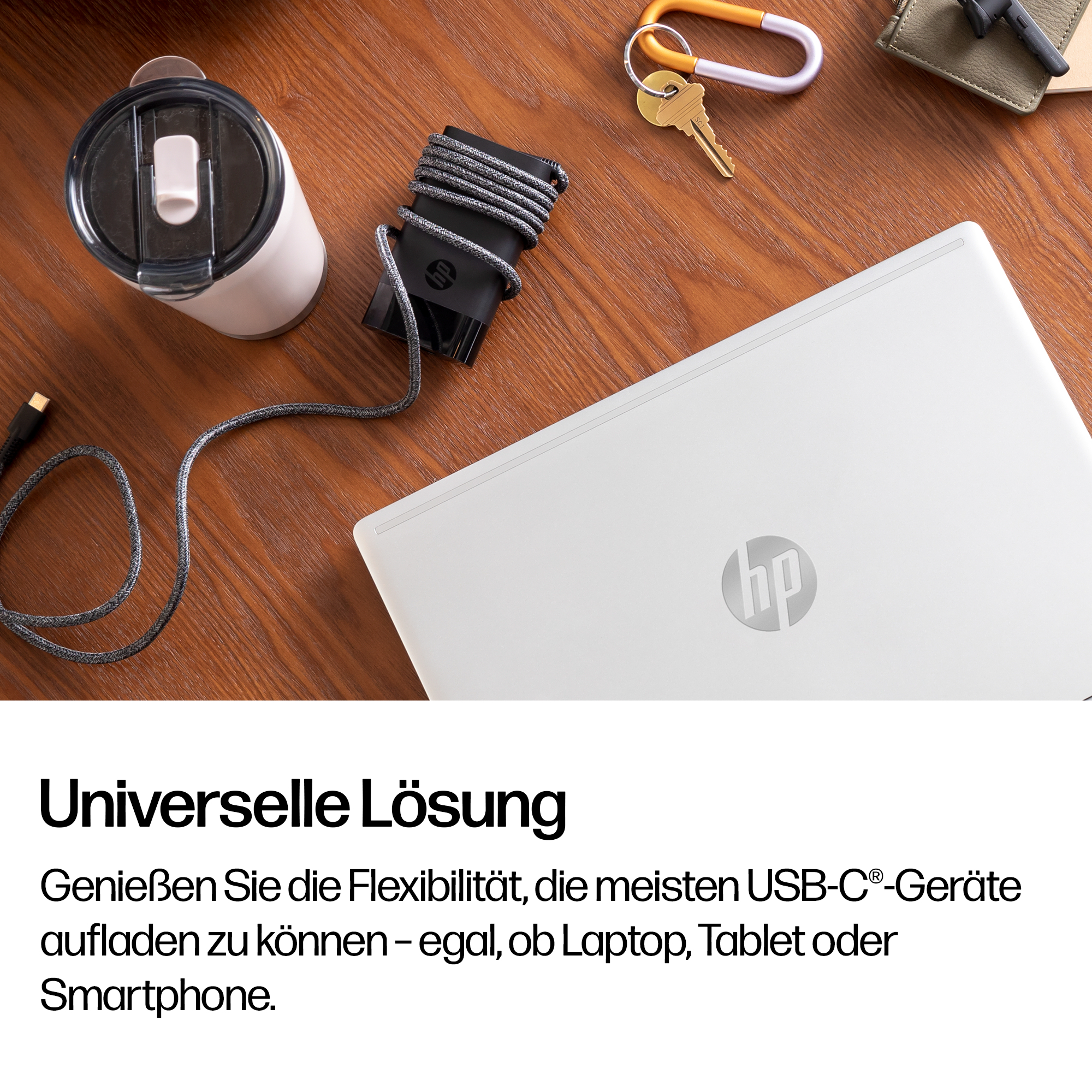 Weiße Thermoskanne, schwarzes Ladegerät, Schlüssel und Laptop auf Holztisch.
