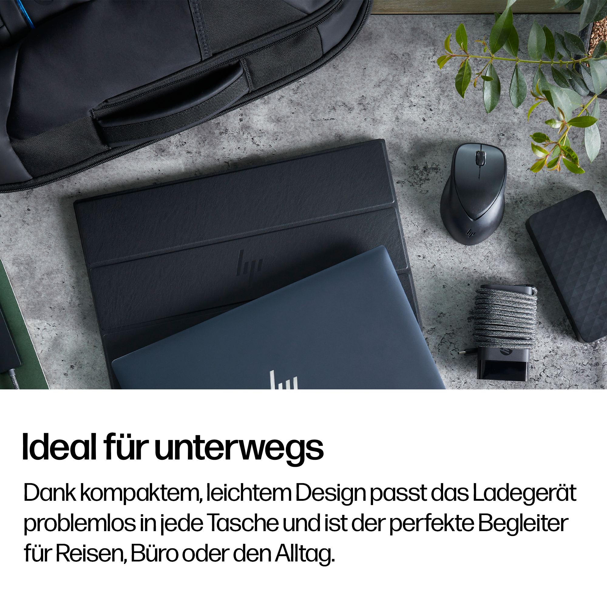 Ein schwarzer Laptop, Maus, Netzteil und externe Festplatte auf einem Schreibtisch.