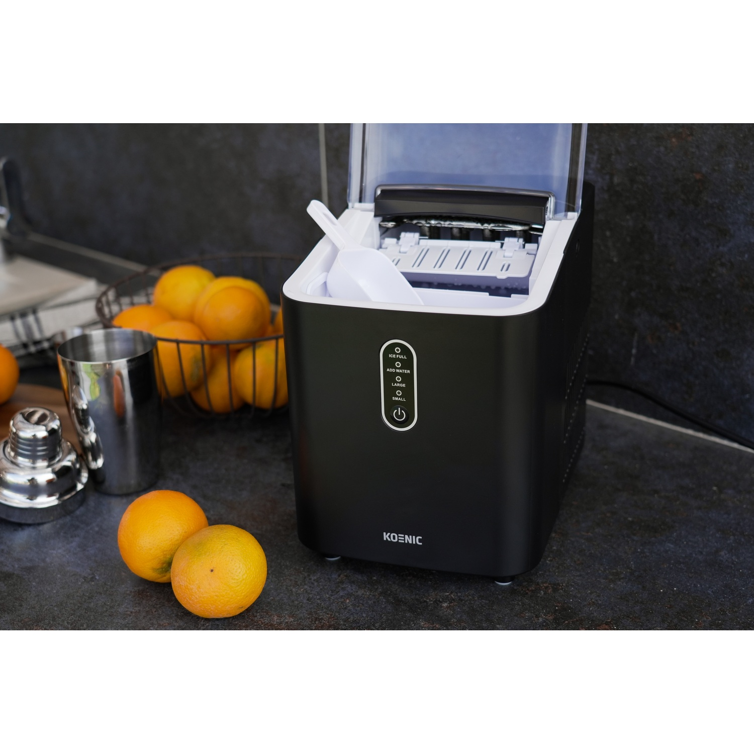 Macchina per il ghiaccio nera con arance e shaker per cocktail.