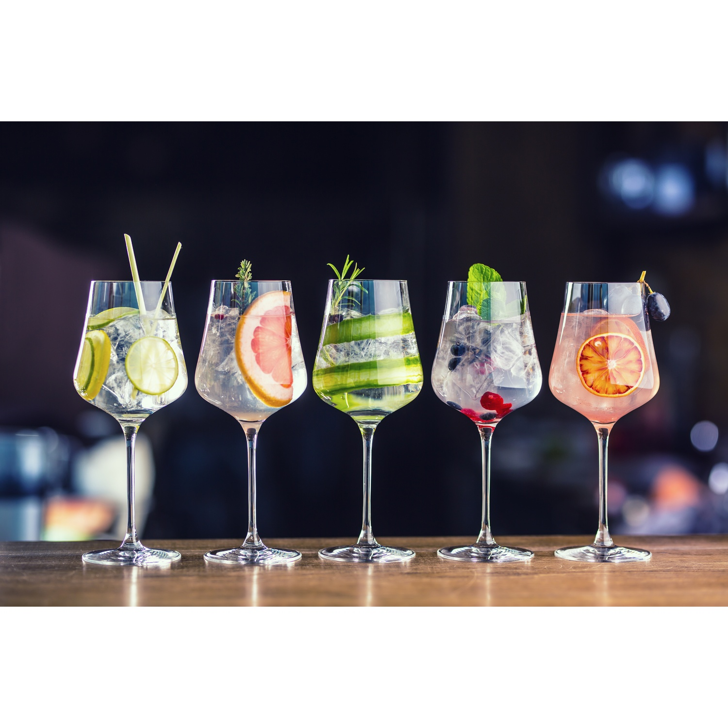 Cinque cocktail con frutta ed erbe in bicchieri su un tavolo di legno.