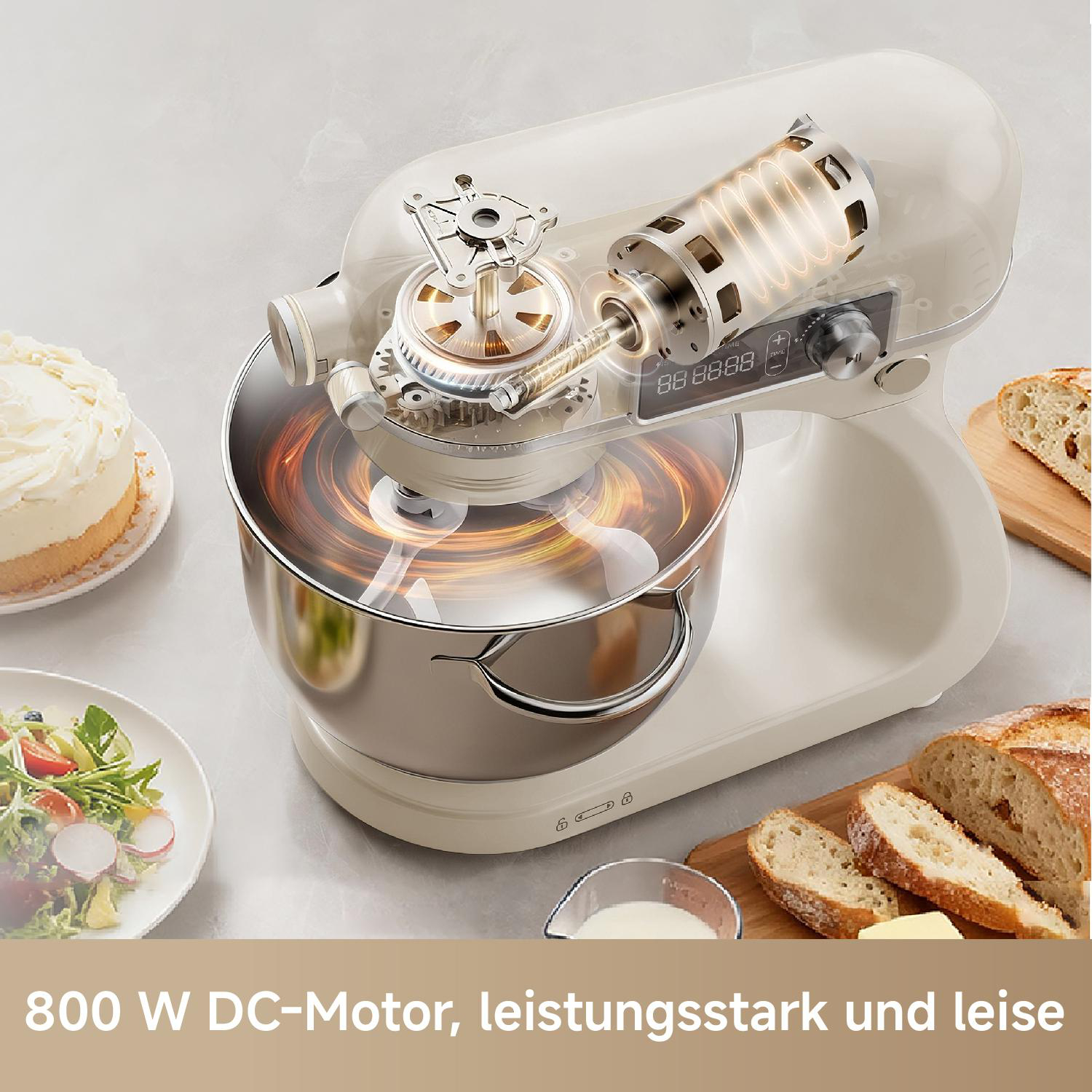 Ein Küchenmixer mit sichtbarem Motor, daneben Kuchen, Salat und Brot.