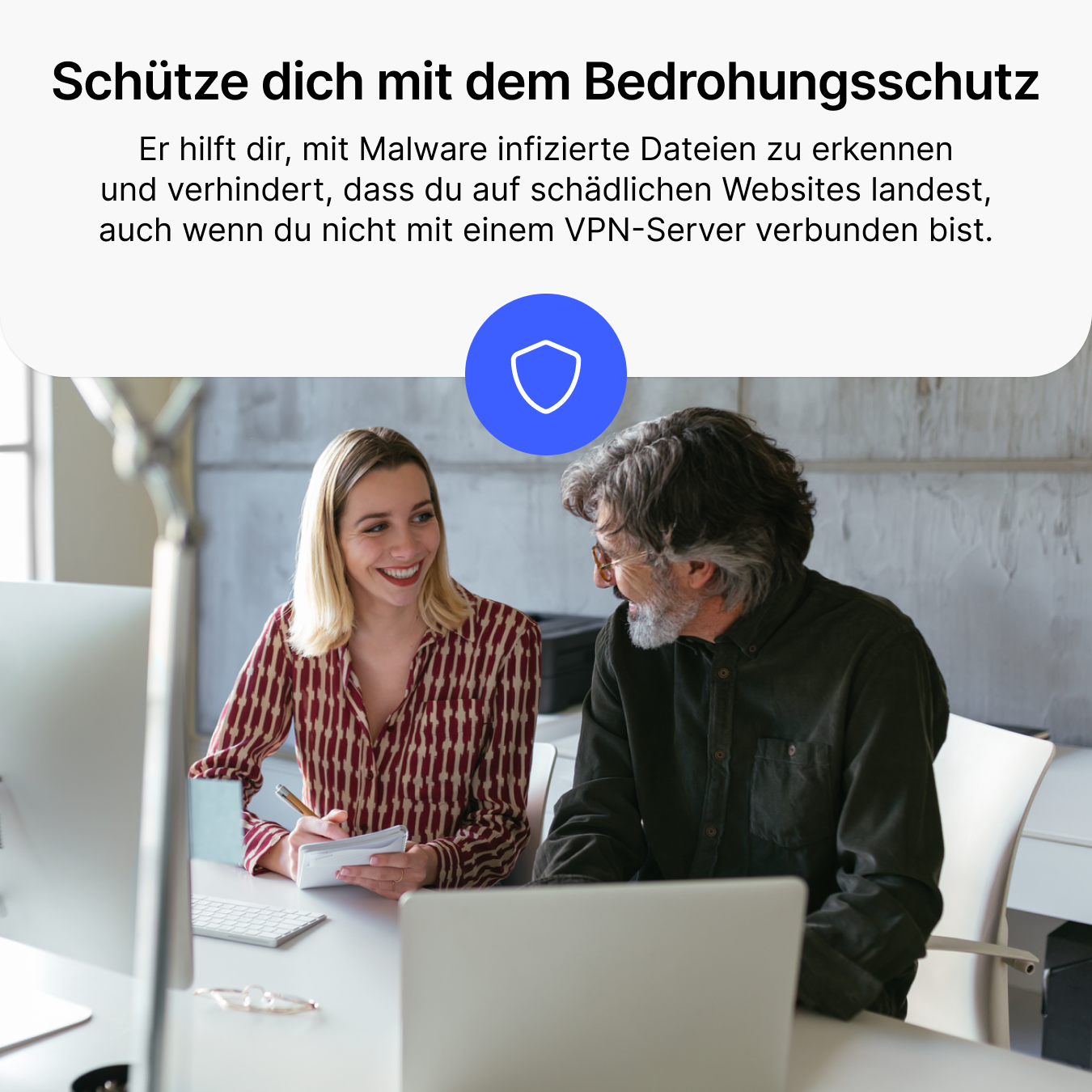Un homme et une femme sont assis à des bureaux et parlent. Une icône de bouclier est visible.