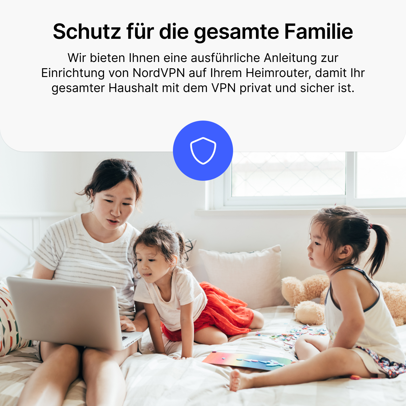 Une mère montre un ordinateur portable à ses enfants assises sur un lit.