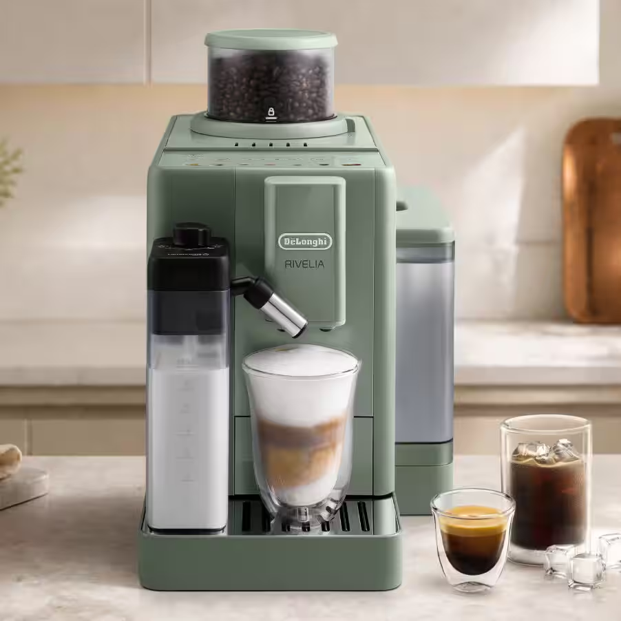 Una macchina da caffè DeLonghi verde salvia con caraffa del latte, che prepara un latte. Due bicchieri di caffè a lato.
