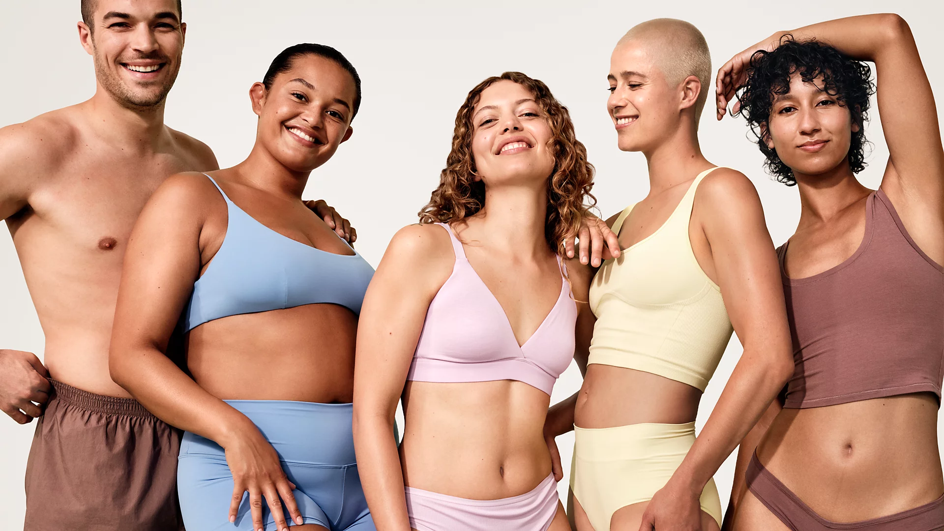 Cinq personnes posant sur fond blanc, portant des sous-vêtements couleur pastel.