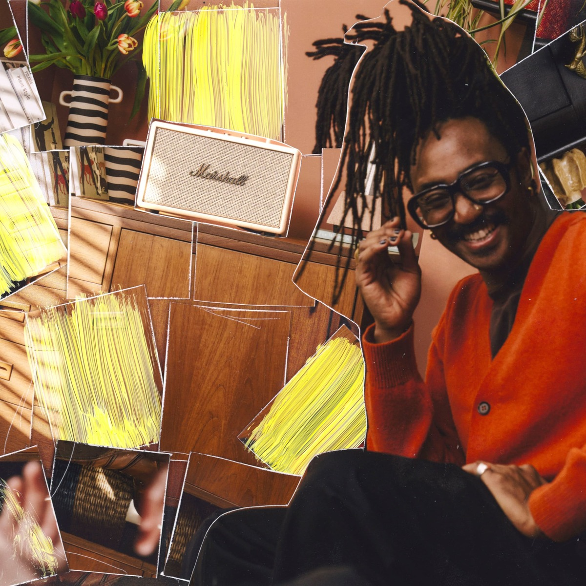 Ein Mann mit Dreadlocks und Brille lacht, neben einem Marshall-Lautsprecher.