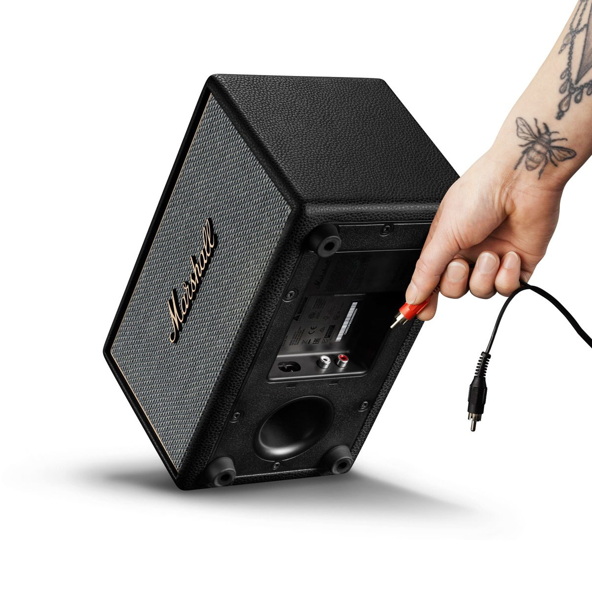 Eine Hand steckt ein rotes RCA-Kabel in einen Marshall-Lautsprecher.
