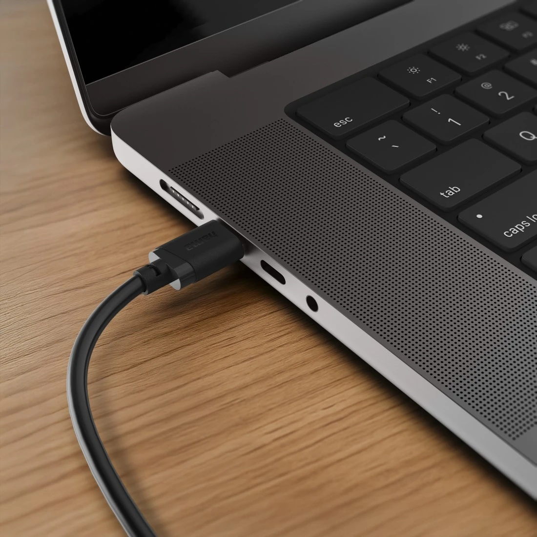 Czarny kabel USB-C jest podłączony do szarego laptopa na drewnianym biurku.