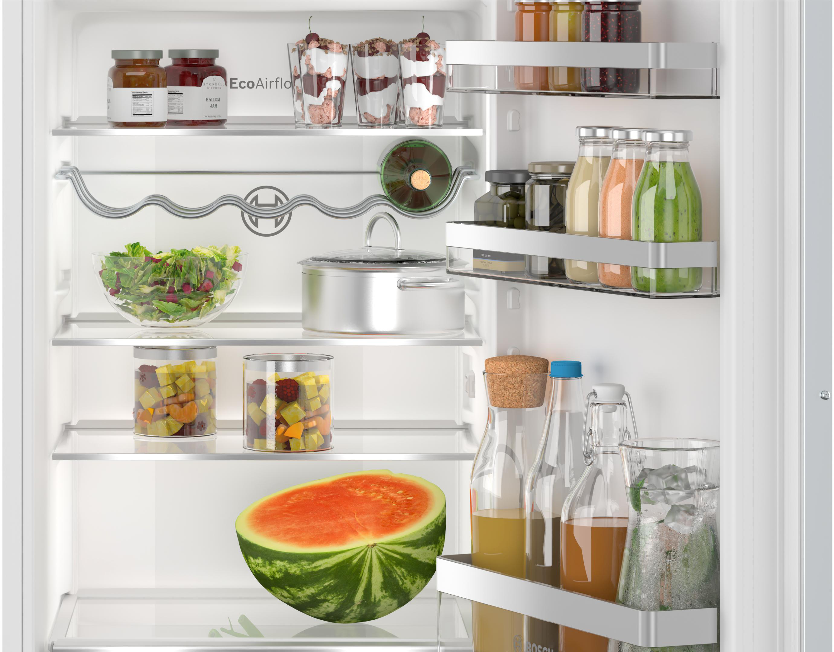 Ein aufgeschnittene Wassermelone liegt in einem Kühlschrank neben Gläsern mit Saft.