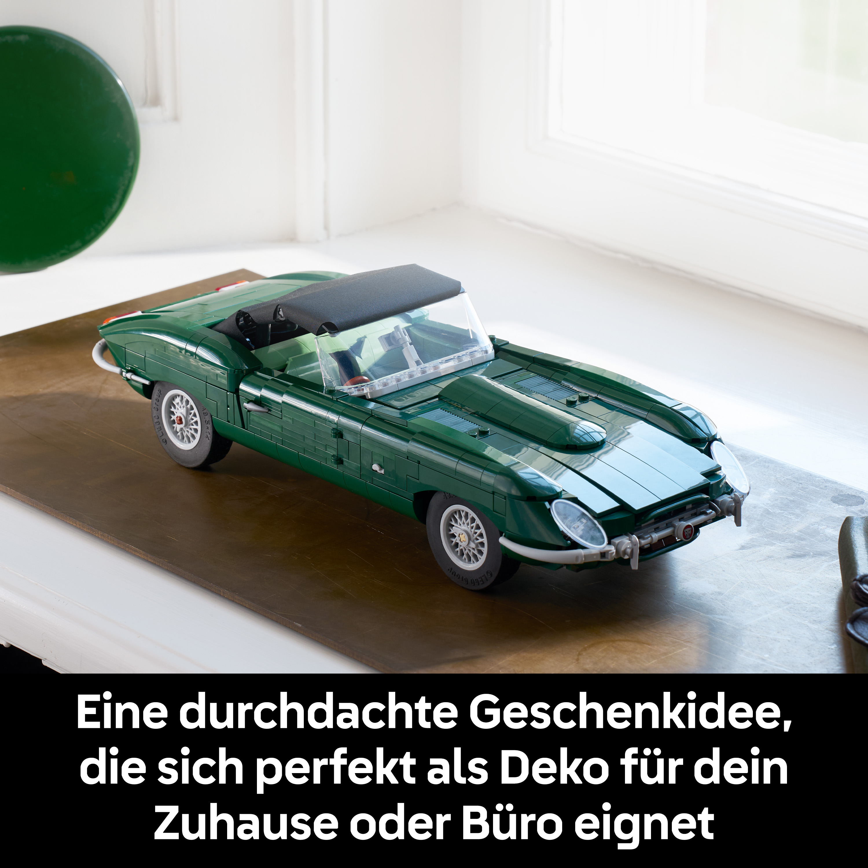Ein grüner Lego-Sportwagen steht auf einem Tisch, mit einem Fenster im Hintergrund.