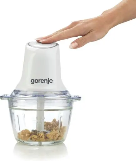 Egy kéz a fehér Gorenje aprítógépre nyom, üveg edényben diókkal.