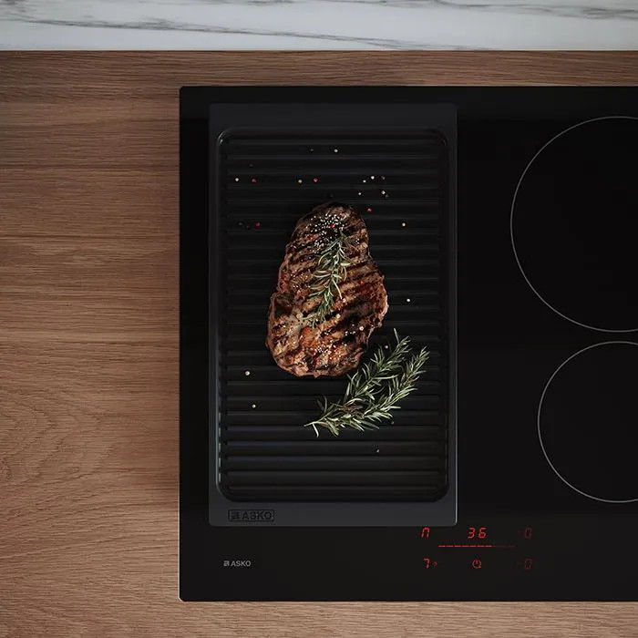 Grillowany stek z rozmarynem na patelni grillowej na płycie indukcyjnej.