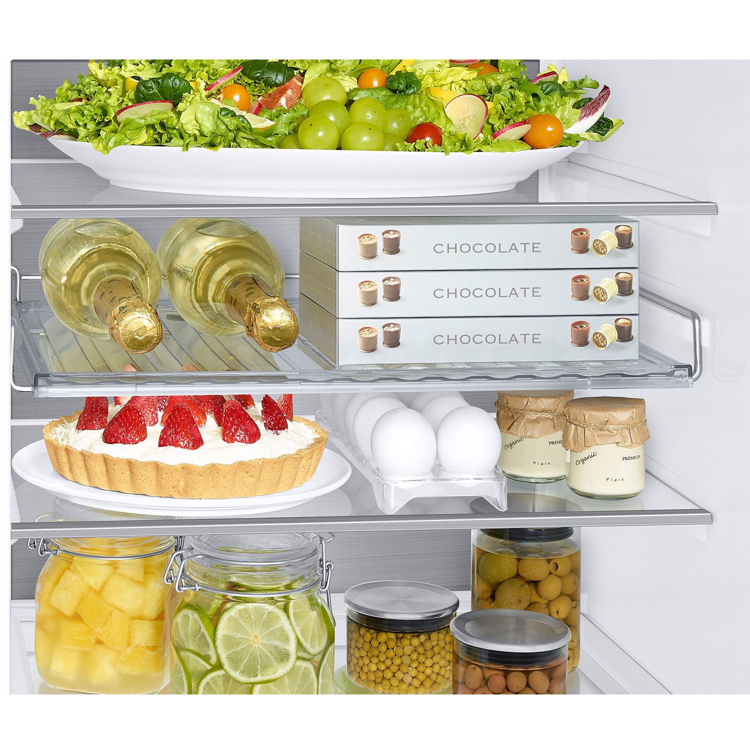 Estantes de refrigerador con ensalada, vino, chocolate, pastel, huevos y frascos.