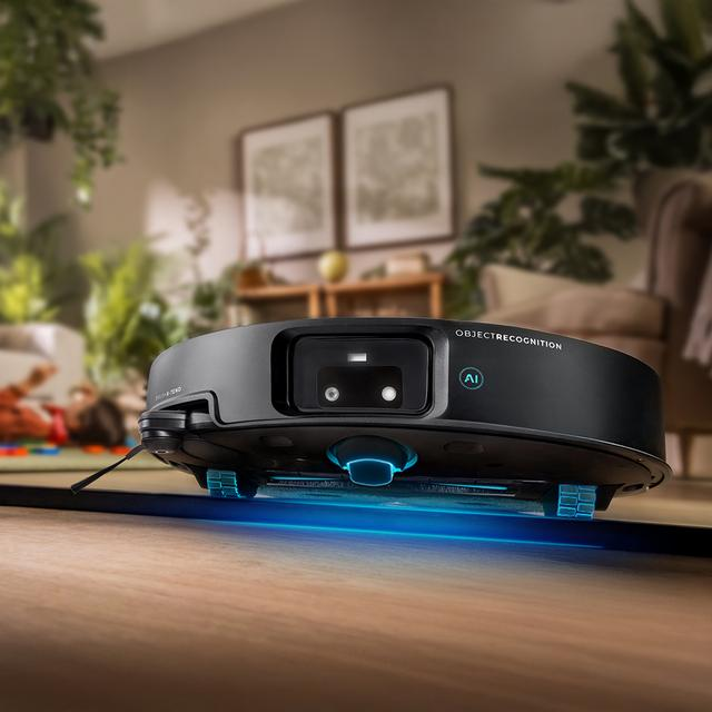 Yapay zeka nesne tanıma özellikli siyah robot süpürge ahşap zeminde geziyor.