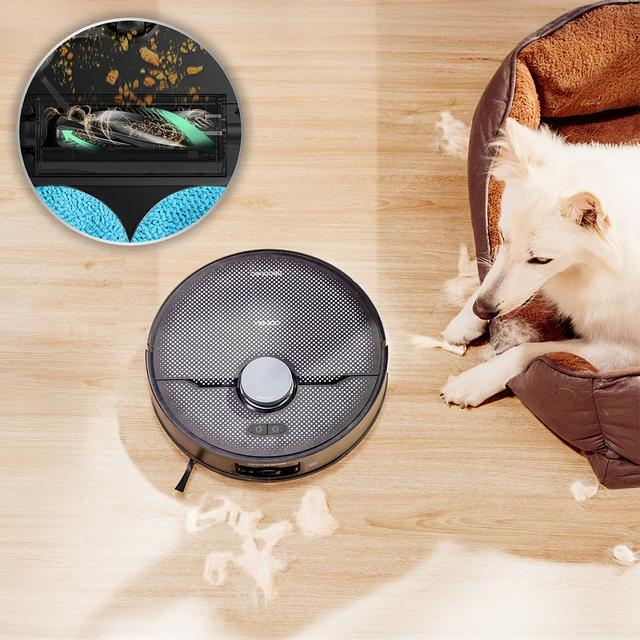 Robot süpürge, yatakta beyaz bir köpeğin yanında ahşap zemini temizler, kir detayında.