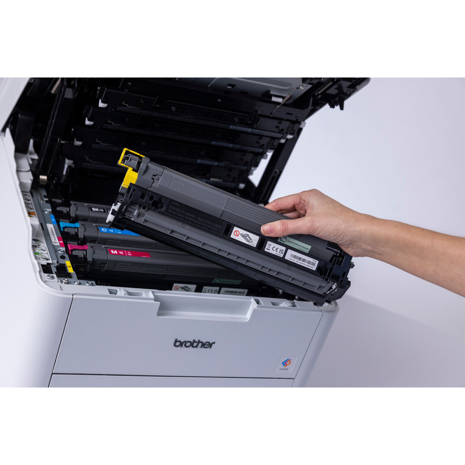 Una mano inserisce una cartuccia toner nera in una stampante a colori Brother.
