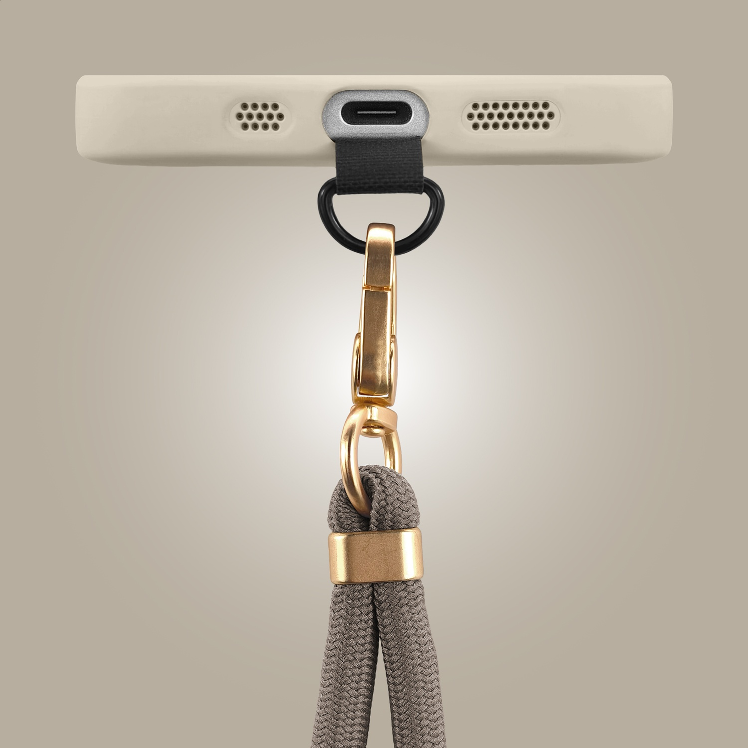 Close-up of a charging port on a light-colored smartphone with a grey lanyard and gold hardware.